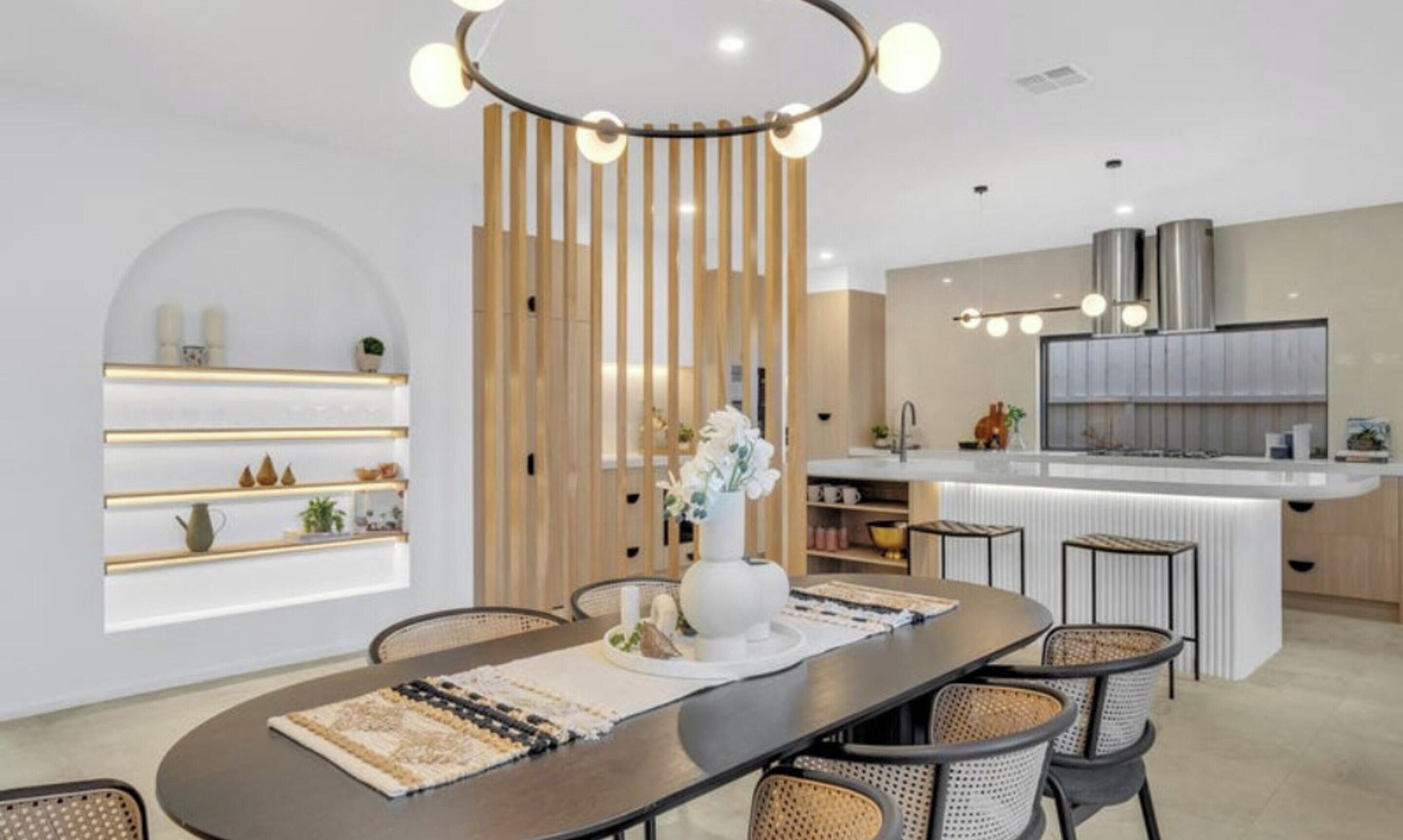 Une cuisine moderne dotée d’un îlot central, de luminaires suspendus et d’un coin repas avec une table ronde et des chaises.