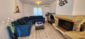 Ein Wohnzimmer mit Ecksofa, Couchtisch, Kamin und einer Pflanze.
