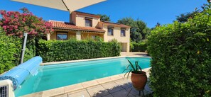Ein Wohnhaus mit Schwimmbad, überdachter Terrasse und gepflegtem Garten.