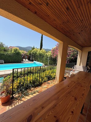 A wooden deck with a pool, surrounded by greenery and a view of mountains. - L'ESTIMADA - 4 CHAMBRES - PISCINE (Argelès-sur-Mer)