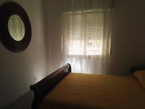 A bedroom with a bed, a round mirror, and a window with sheer curtains. - Apartment 'The Serendipity' (Lido di Ostia)