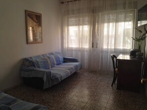 A living room with a sofa, a table, and a chair. - Apartment 'The Serendipity' (Lido di Ostia)