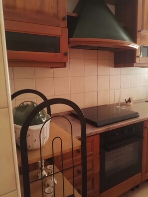A kitchen with wooden cabinets, a black countertop, and a stove. - Apartment 'The Serendipity' (Lido di Ostia)