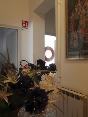 Un couloir avec un panneau indiquant l’emplacement d’un extincteur, une porte, un radiateur et un tableau accroché au mur.