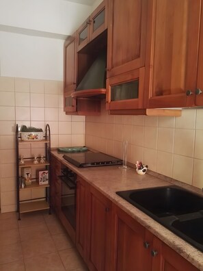 A kitchen with wooden cabinets, a stainless steel sink, and a built-in oven. - Apartment 'The Serendipity' (Lido di Ostia)
