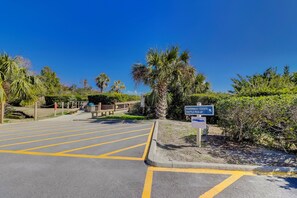 A parking lot with yellow lines and a sign indicating a shuttle pick-up point. - Sunset Rentals | Hilton Head Resorts 3103 (Hilton Head Island)