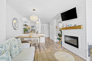 A modern kitchen with white cabinetry, a wooden dining table, and a built-in fireplace. - Sunset Rentals | Hilton Head Resorts 3103 (Hilton Head Island)