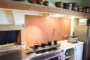 A kitchen with a brick backsplash, a gas stove, and a microwave. - Podere di Piero nel cuore delle colline lucchesi (LUCCA)