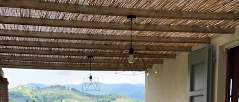 An outdoor patio with a table set for dining, surrounded by chairs, and a view of the countryside.
