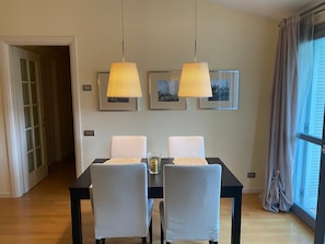 Ein Essbereich mit einem schwarzen Tisch, zwei grauen Stühlen und zwei Pendelleuchten.