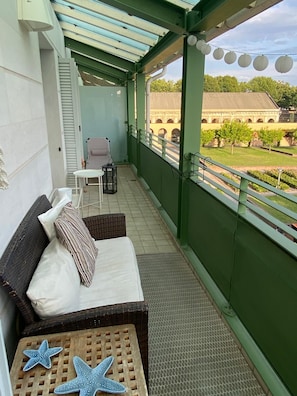 Ein Balkon mit gepolsterten Sitzgelegenheiten, einem kleinen Tisch und dekorativen Seesternen.