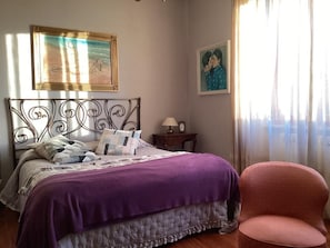 A bedroom with a bed, a chair, a nightstand, and a painting on the wall. - Casa Riccardo in Villa (BARGA)
