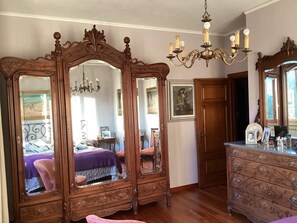 Una habitación con un espejo grande, muebles de madera y un candelabro.