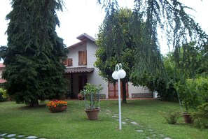 Una casa con jardín, plantas en macetas y un sendero que lleva a la entrada.