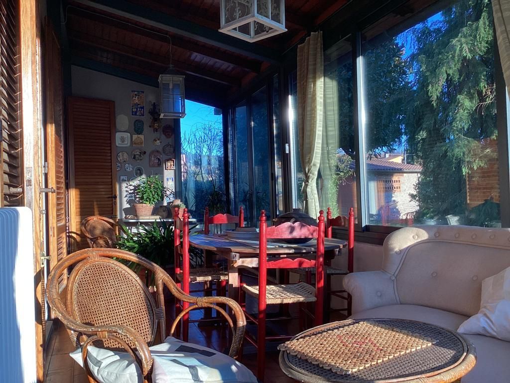 A sunlit room with a dining table, chairs, and a sofa.