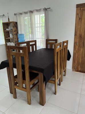 A dining area with a wooden table and chairs, a water dispenser, and a window with curtains.