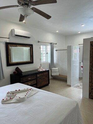 A bedroom with a bed, a dresser, a mirror, a ceiling fan, and a window.