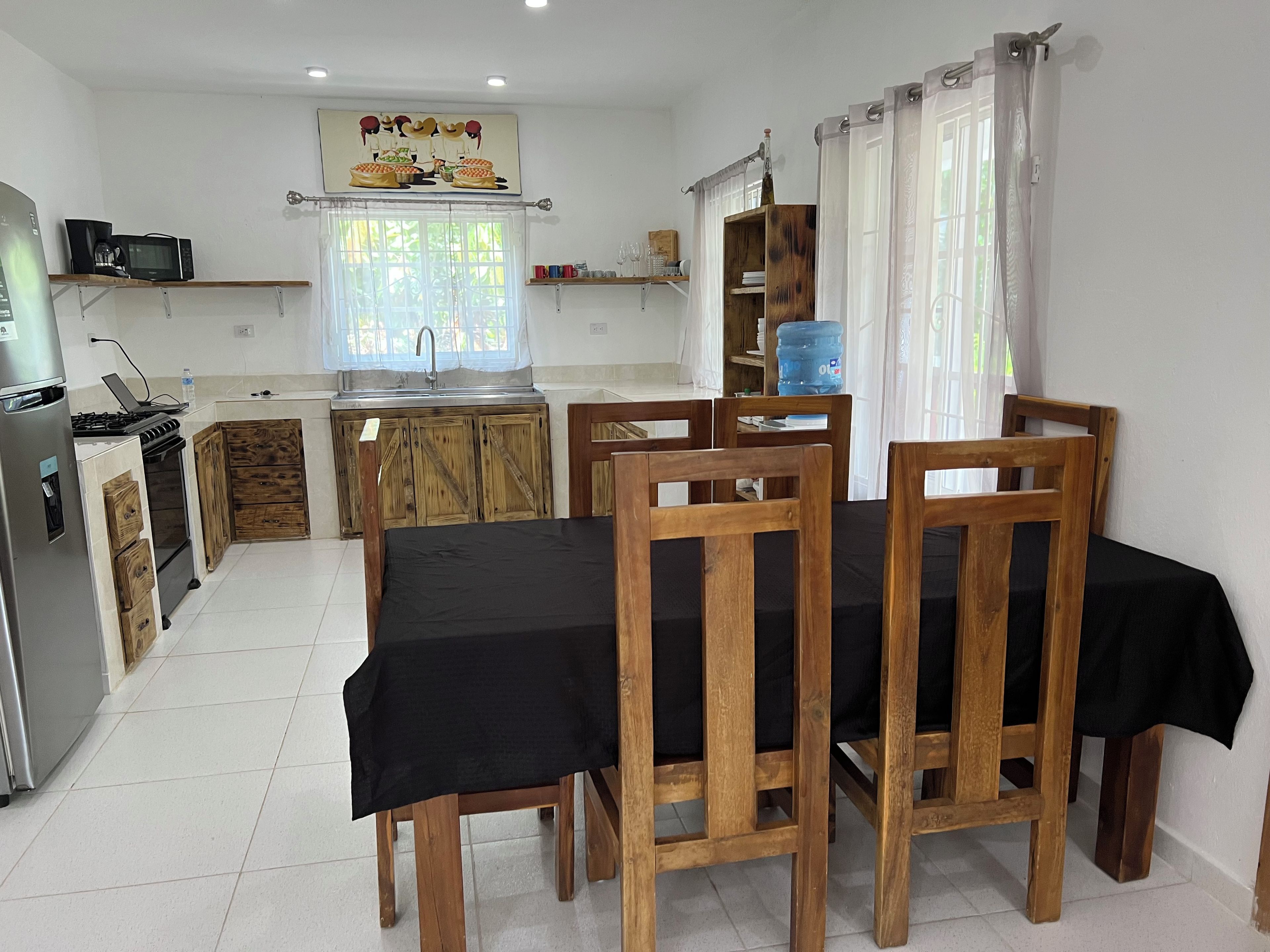 Une cuisine compacte avec des meubles de rangement en bois, un évier et un coin repas comprenant une table et des chaises.