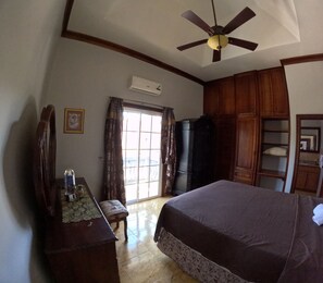 A bedroom with a bed, a ceiling fan, a wardrobe, a desk with a chair, and a window with curtains. - Sukasa Ville 3 beautiful bedroom
Perfect for family
The villa edition (Trelawny)