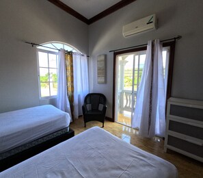 A room with two beds, a chair, a balcony door, and an air conditioning unit. - Sukasa Ville 3 beautiful bedroom
Perfect for family
The villa edition (Trelawny)