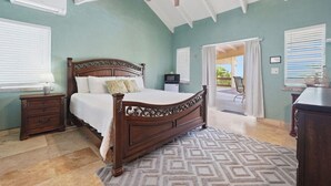 Een slaapkamer met een houten bed, een nachtkastje, een bureau en een plafondventilator.