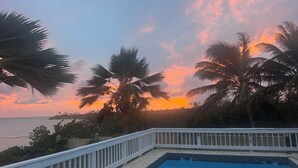 A swimming pool with a white railing, palm trees, and a sunset view. - Luxury 2 bedroom Waterfront Villa Private Pool, & Spacious Deck (Frederiksted)