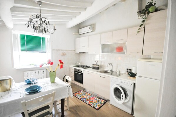 A compact kitchen with a dining area, a washing machine, and a radiator. - Casa del Papavero city center (LUCCA)