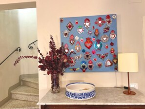 A staircase with a vase of red flowers, a decorative plate, and a wall with a heart-themed artwork. - Casa Albertina central/ac 2/bathrooms (LUCCA)