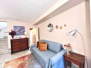 A living room with a sofa, a wooden dresser, a mirror, and a lamp. - Casa Albertina central/ac 2/bathrooms (LUCCA)