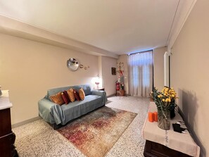 A living room with a sofa, a coffee table, a mirror, and a vase with flowers. - Casa Albertina central/ac 2/bathrooms (LUCCA)