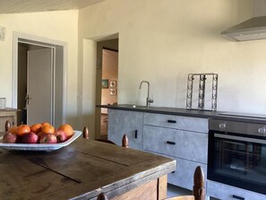 Eine Küche mit Holztisch, Obstschüssel, modernem Backofen und Edelstahlarmatur.