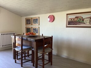 A dining area with a wooden table and chairs, a clock on the wall, and framed pictures. - Mansarda in Villa Riccardo (BARGA)