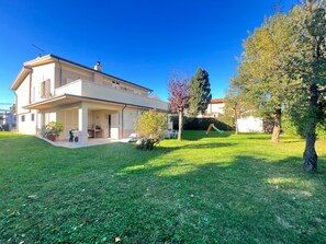 Ein zweigeschossiges Haus mit einer überdachten Veranda und einem Rasen.