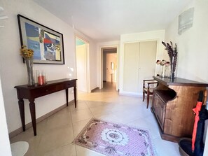 A hallway with a wooden console table, a framed abstract painting, a vase with flowers, and a patterned rug. - Villa Paola vicino al centro storico (LUCCA)
