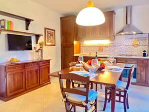Une cuisine moderne avec des meubles en bois, une table à manger pour quatre personnes et un grand luminaire suspendu.