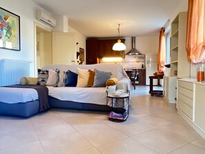 A modern living room with a sofa, a coffee table, and a kitchen in the background. - Villa Paola vicino al centro storico (LUCCA)