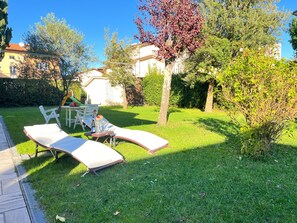 Ein Garten mit Rasen, einem Tisch mit Stühlen und einem kleinen Baum.