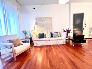 Un salon avec un canapé, un fauteuil, une lampe et un radiateur.