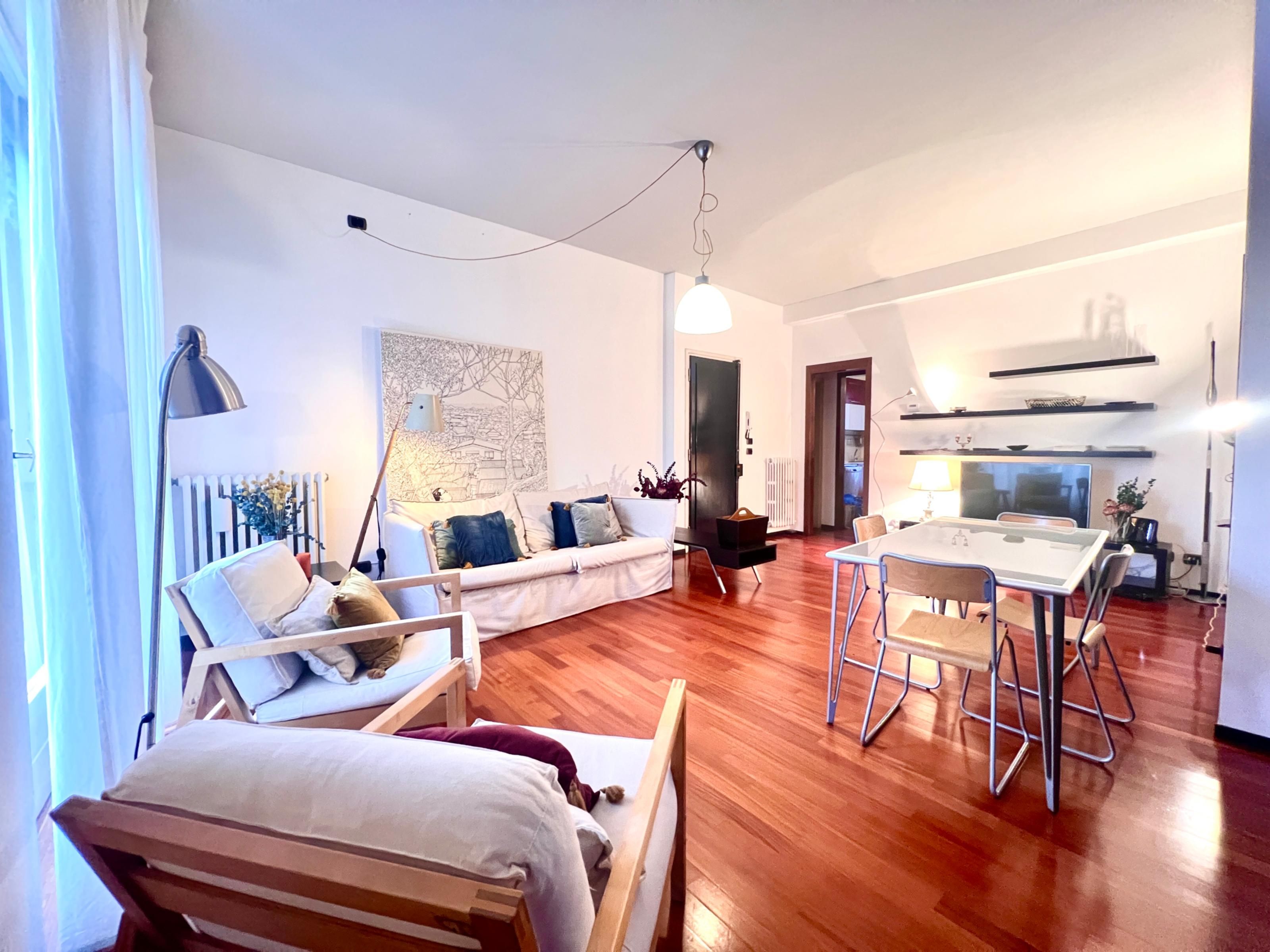 A modern living room with a sofa, a dining table, and a kitchen area.