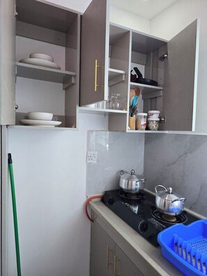 A kitchen with a gas stove, a blue plastic container, and various kitchen utensils. - Matunda homes 
Cozy.Classy.Beautiful (Mombasa)