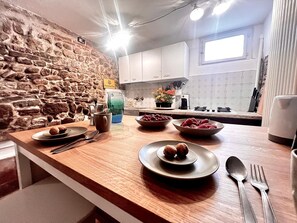 A kitchen with a stone wall, wooden countertop, and white cabinets. - Casa in Pelleria nel cuore del centro storico (LUCCA)