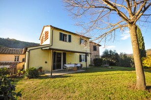 A two-story house with a covered patio and a dining table set outside. - Casa il Tiglio nel cuore delle colline lucchesi (LUCCA)