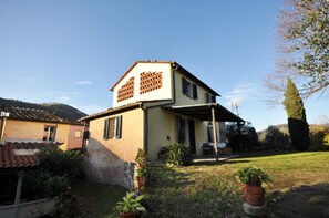 Une maison à deux étages avec un porche abrité et un petit jardin.