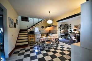 Une cuisine avec un carrelage à motifs, une table à manger avec des chaises, un escalier et une bibliothèque.