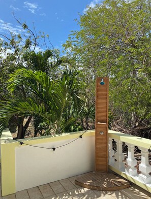 A wooden structure with a vertical panel, surrounded by a white fence with decorative posts, set against a backdrop of lush greenery and trees. - Lovely 2BR Villa Plus a New Pool-Stunning Views of St. Maarten (George Hill)