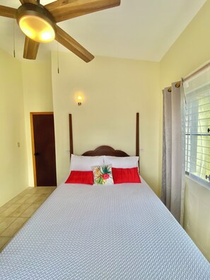 A room with a bed, a ceiling fan, a window with curtains, and a door. - Lovely 2BR Villa Plus a New Pool-Stunning Views of St. Maarten (George Hill)
