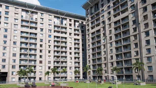 A swimming pool with clear blue water, surrounded by a well-maintained lawn and palm trees. - Sandton Wespoint Luxury Apartments (Sandton)