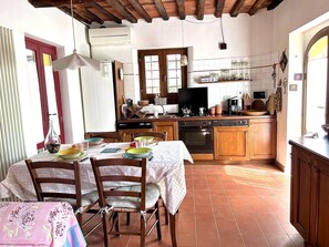 Une cuisine avec des meubles de rangement en bois, une table à manger avec des chaises et un mur recouvert de carreaux.