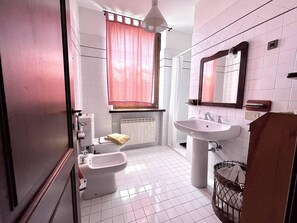 A bathroom with a toilet, bidet, sink, and a mirror. - Casa Silvia a piedi dalle mura AC (LUCCA)