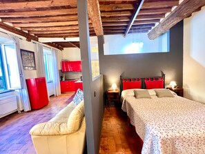 A room with a bed, a sofa, a kitchen area, and a window. - civico 12 appartamento in centro storico (LUCCA)